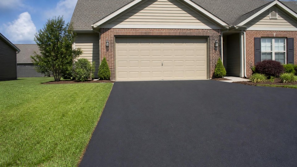 Newly paved residential driveway with a clean edge where the asphalt meets the lawn