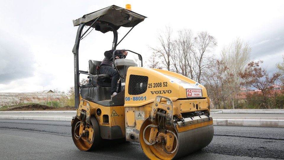 Steel-drum roller compacting a fresh asphalt mat on a newly paved surface
