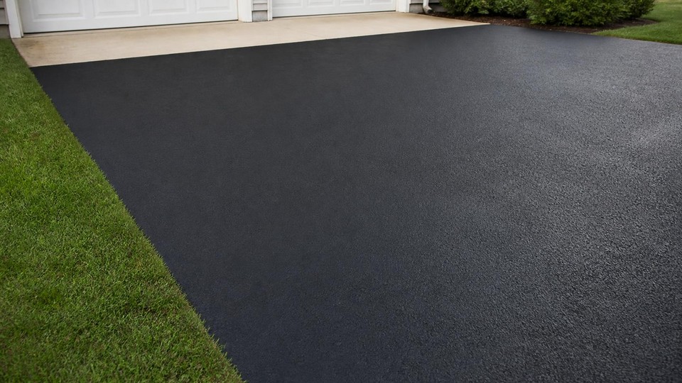 Freshly sealcoated driveway with a uniform black finish and a straight cut at the garage apron