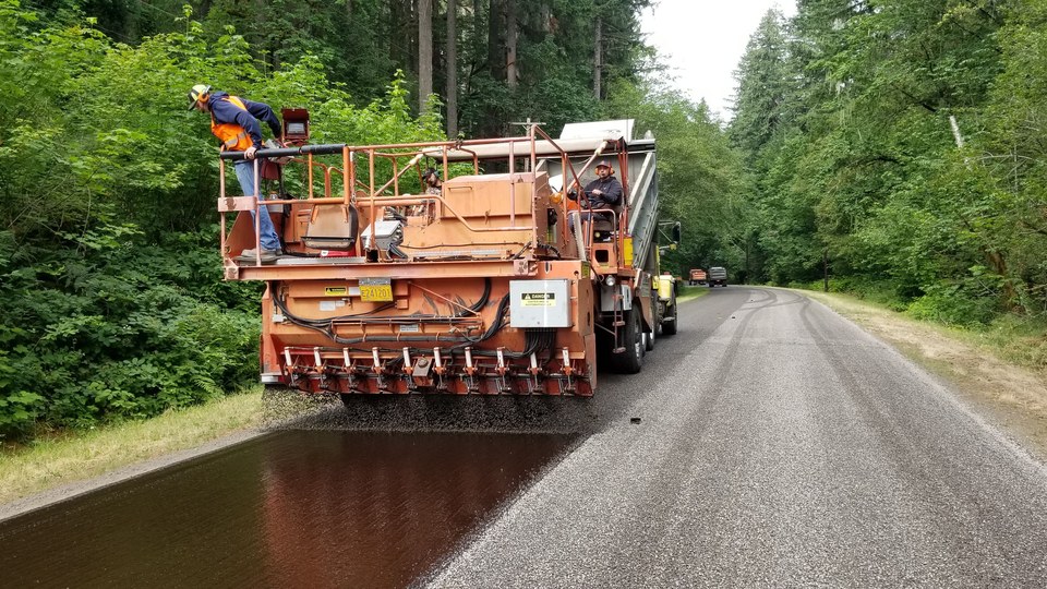 Chip spreader laying stone over fresh binder during a tar-and-chip application